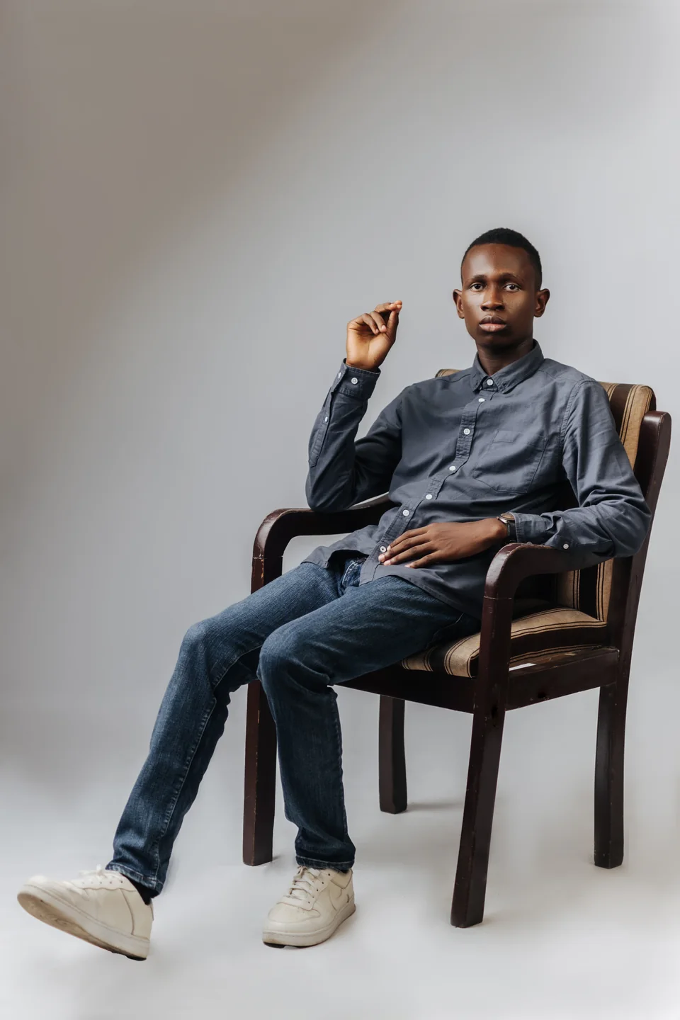 Divine Jemegbe seated in a grey shirt and jeans.